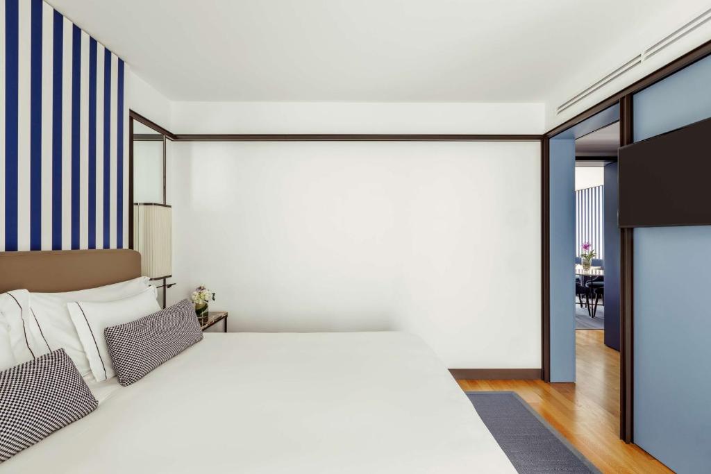 a bedroom with a white bed and a dining room at Tivoli Portopiccolo Sistiana Wellness Resort & Spa in Sistiana