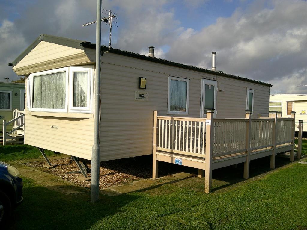 a tiny house with a porch and a deck at Highfields Rio 6 berth blow heated in Skegness
