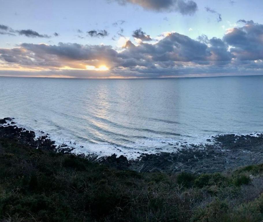 un coucher de soleil sur un plan d'eau avec le soleil couchant dans l'établissement Schönes Ferienhaus in Strandnähe in Privatresidenz Alouettes & Moineaux in der Nahe Mont St Michel, à Hauteville-sur-Mer