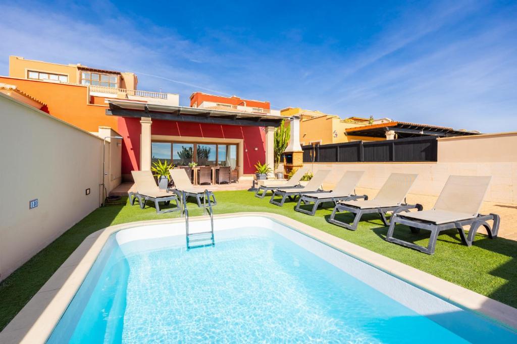 a backyard with a swimming pool and a patio with chairs at Villa Mariposas Caleta in Caleta De Fuste
