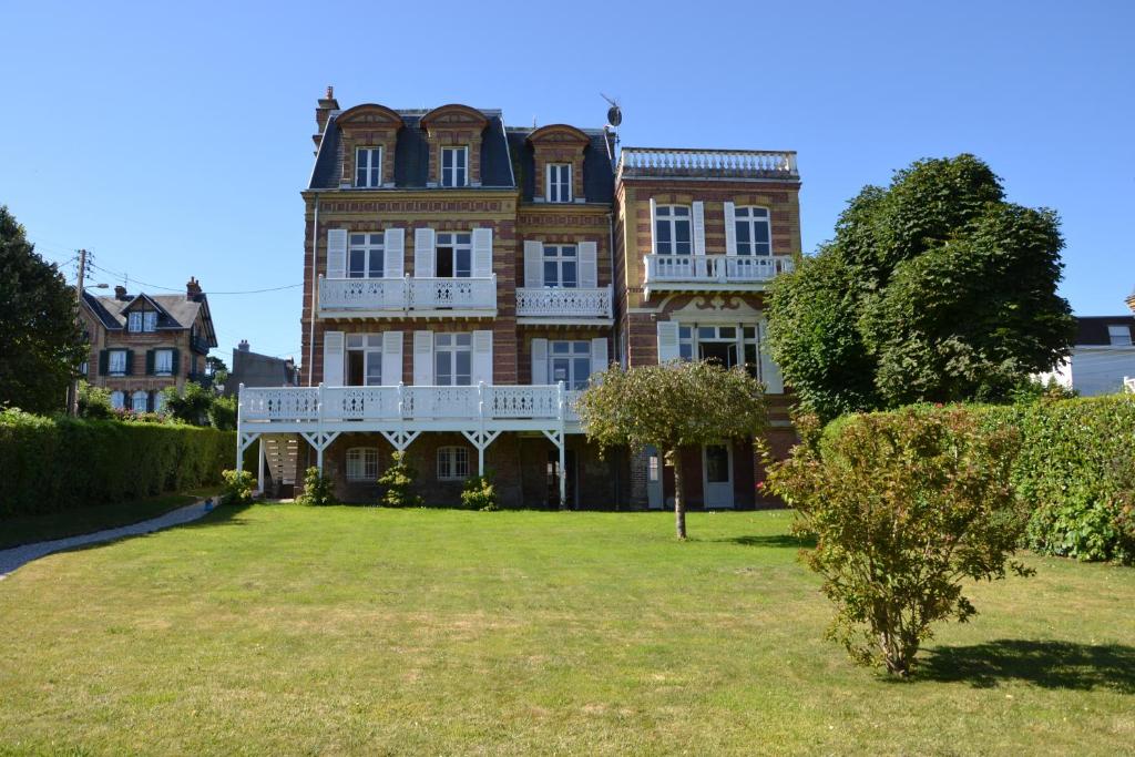 un gran edificio de ladrillo con un gran patio en Guesthouse La Mascotte en Villers-sur-Mer