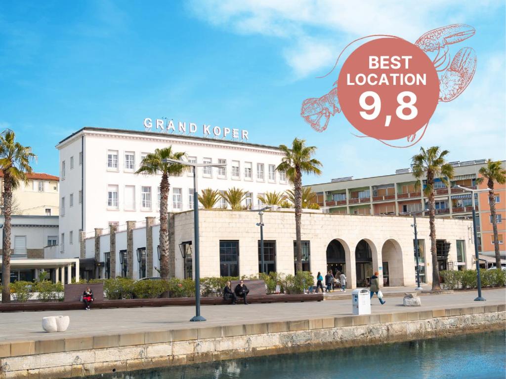 a large white building with a sign that reads best location at Hotel Grand Koper in Koper