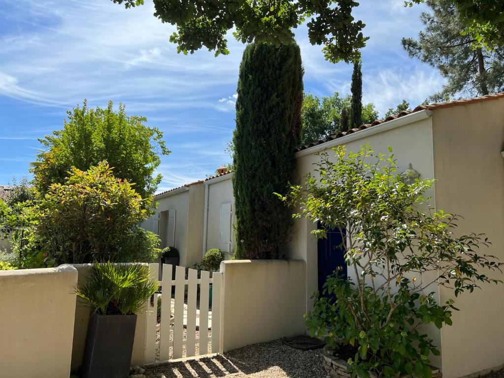 Une clôture blanche avec un grand arbre derrière elle dans l'établissement Maison lumineuse avec jardin, au Château-dʼOléron