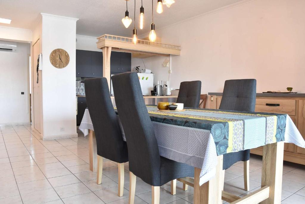 une table à manger avec des chaises noires et une cuisine dans l'établissement Appartement 3 pièces GRUISSAN GN380-C67, à Gruissan