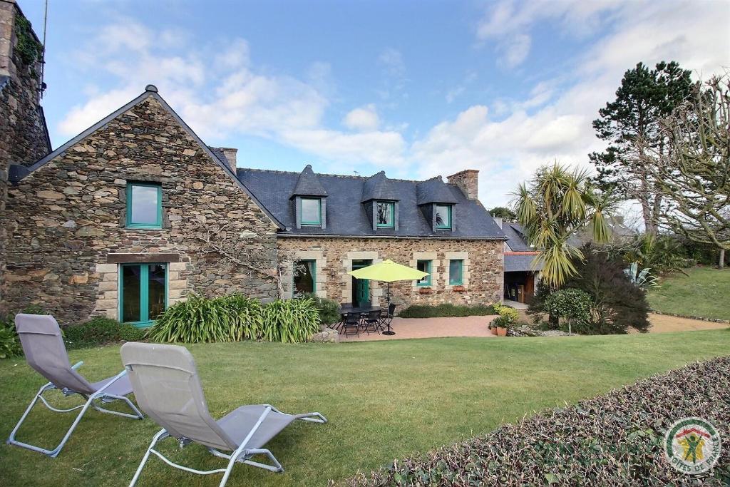 a house with two chairs and a yellow umbrella at Les hauts de kergiquel in Paimpol