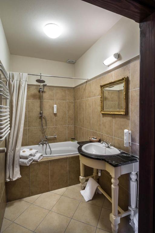 Elegant bathroom with tiled walls, bathtub, vintage mirror, and a classic sink.