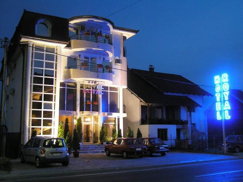 un edificio con coches aparcados delante de él por la noche en Hotel Royal, en Kraljevo