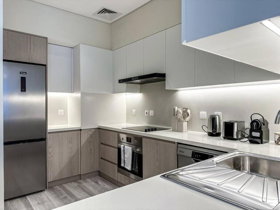 a kitchen with white cabinets and stainless steel appliances at Fantastic flat in TiaraResidence in Dubai