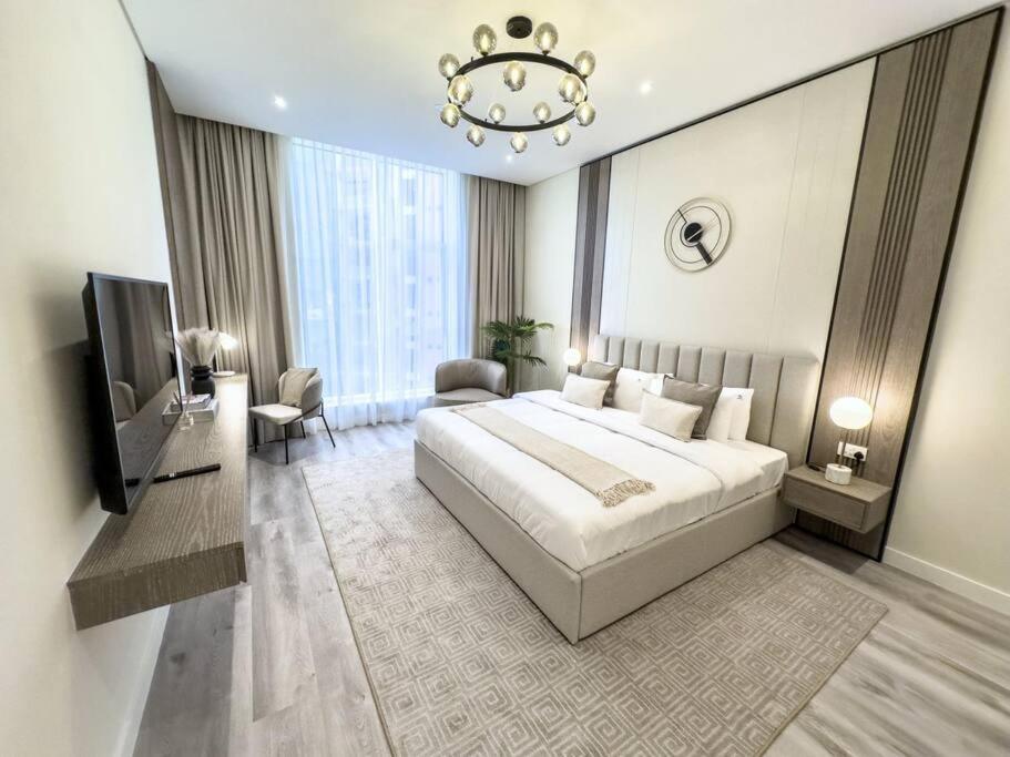 a bedroom with a large bed and a chandelier at Fantastic flat in TiaraResidence in Dubai