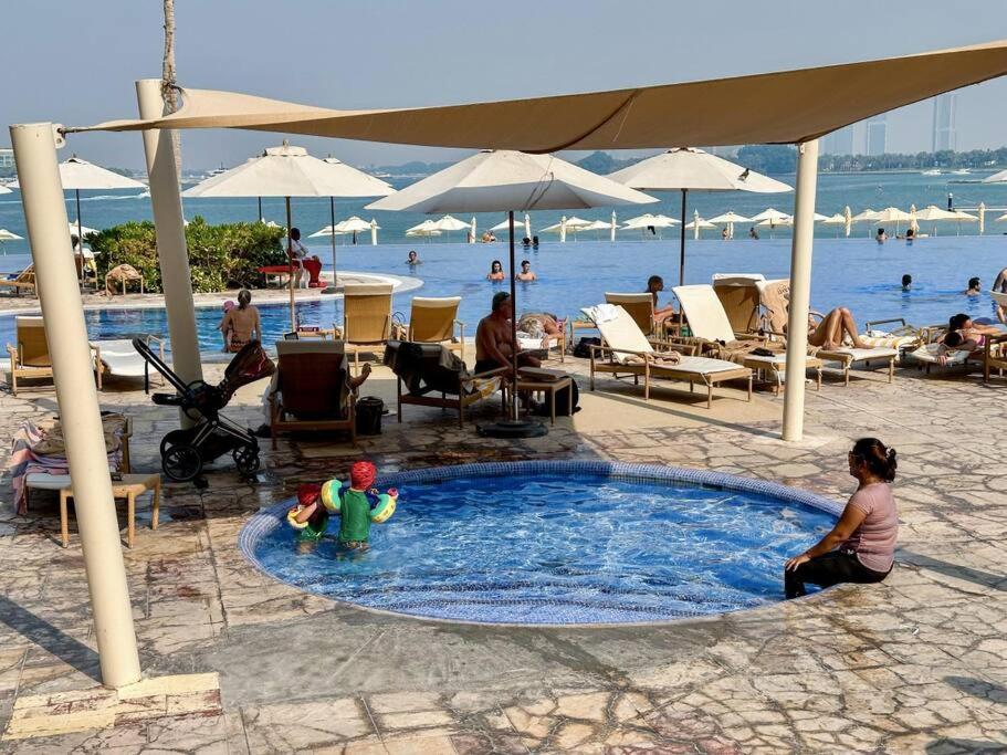 a child sitting in a swimming pool at a beach at Fantastic flat in TiaraResidence in Dubai