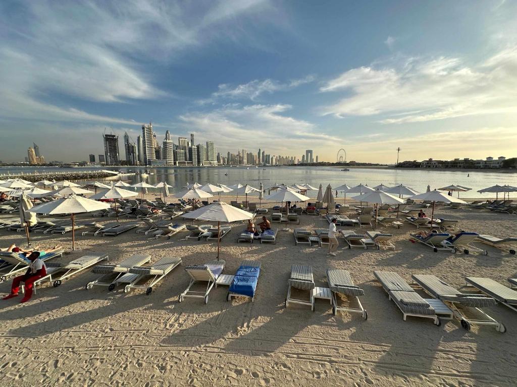 a beach with chairs and umbrellas and a city at Renovated Marina view apartment in Oceana in Dubai