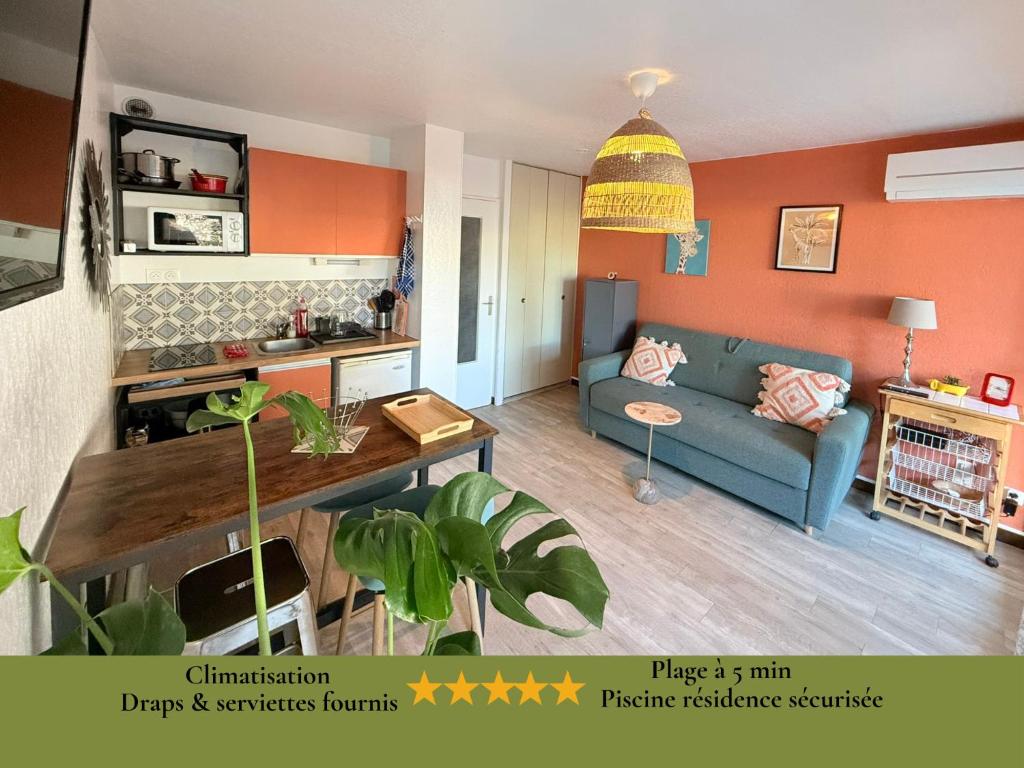 - un salon avec un canapé bleu et un mur orange dans l'établissement COSY APPART LE COUCHANT 4 Pers - CLIM, BALCON,PISCINE,PLAGE 5 MIN, LA GRANDE MOTTE, à La Grande Motte