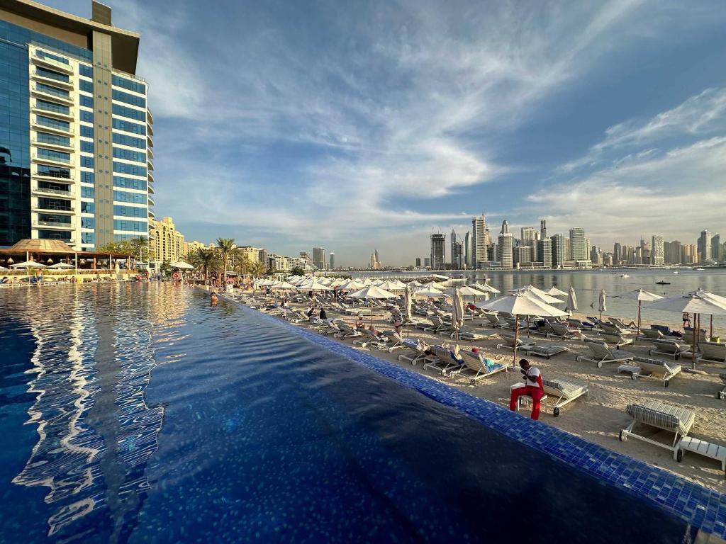 a swimming pool with chairs and a city skyline at Renovated Marina view apartment in Oceana in Dubai