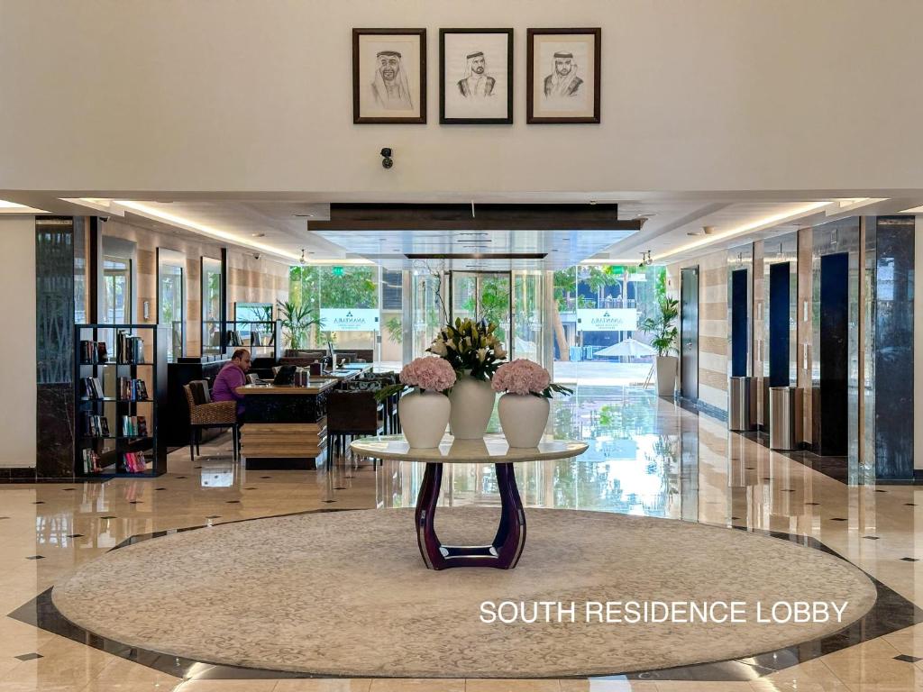 迪拜Upgraded Gorgeous 1BR at 5 Star Resort的大堂设有一张桌子,上面有两瓶花