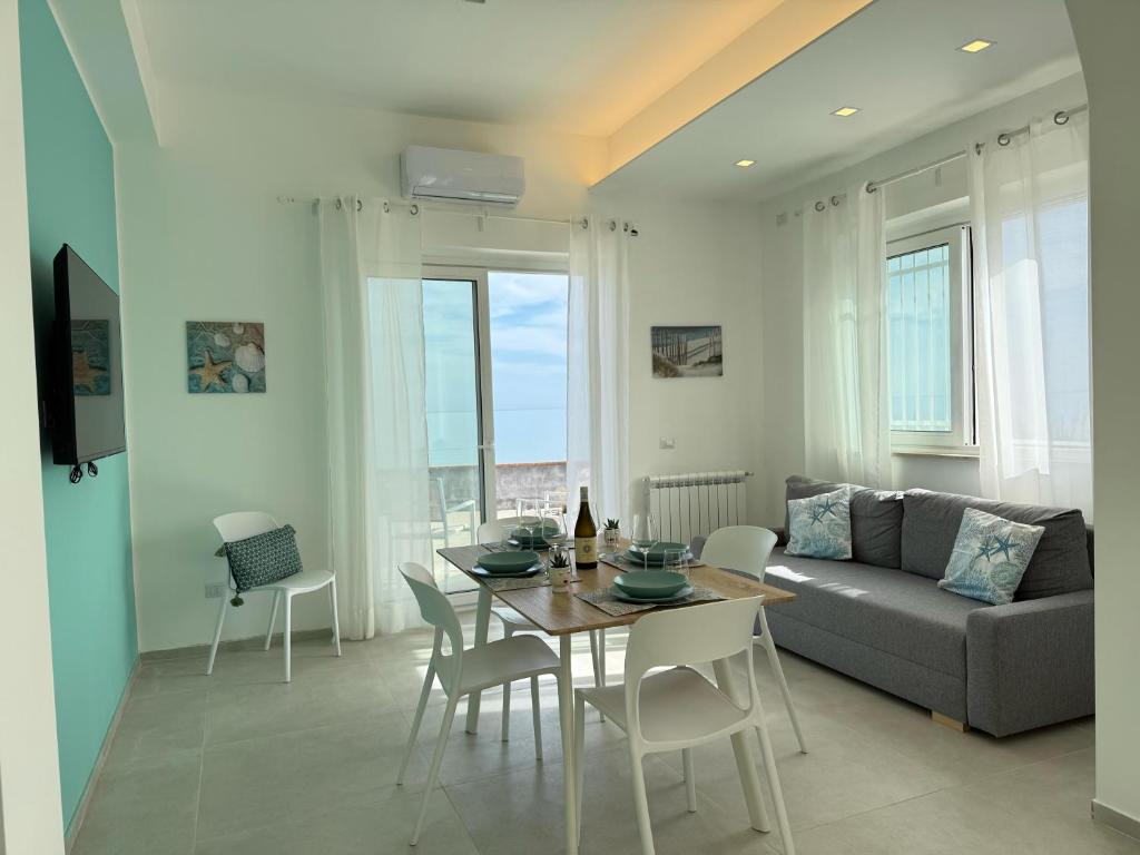 Una sala de estar con un sofá, una mesa y sillas. en Villa Acquamarina, en Villaggio San Leonardo