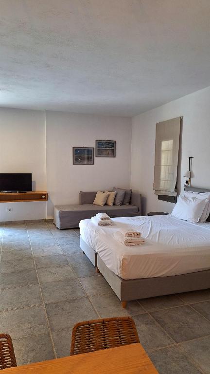 a bedroom with a large bed and a couch at Margo Beach Hotel in Gythio