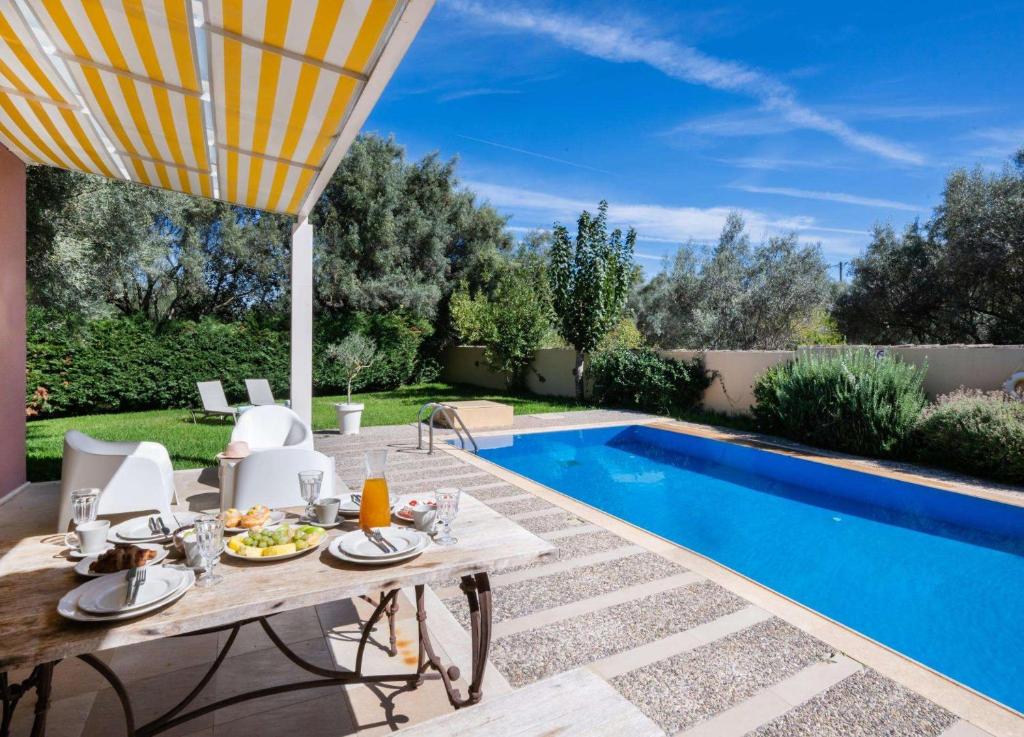 un tavolo da pranzo e sedie accanto alla piscina di Maria by Vintage Travel a Città di Lefkada