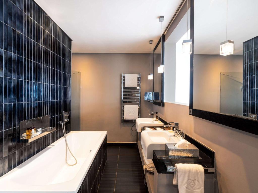a bathroom with two sinks and a bath tub at Sofitel Casablanca Tour Blanche in Casablanca