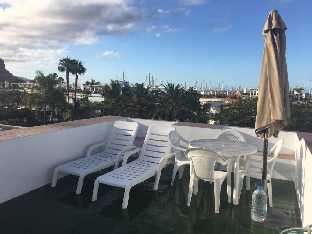 un balcon avec une table, des chaises et un parasol dans l'établissement Castillete 5 by El Sirocco, à Puerto de Mogán