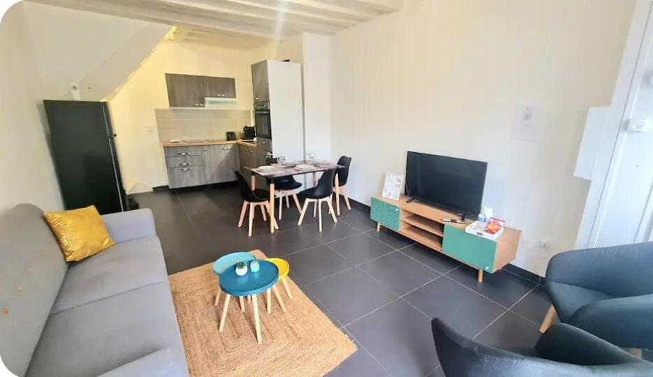 a living room with a couch and a table with chairs at Cœur de Ville - familial - Parking gratuit - WIFI in Conches-en-Ouche