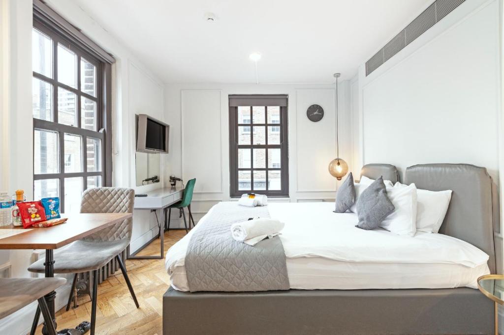 a white bedroom with a bed and a desk at London Paddington Apartments in London