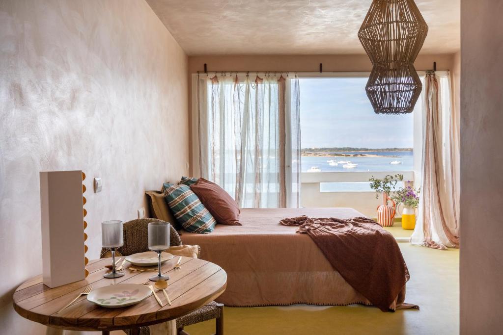 a bedroom with a bed and a table and a window at Formentera Especial in La Savina