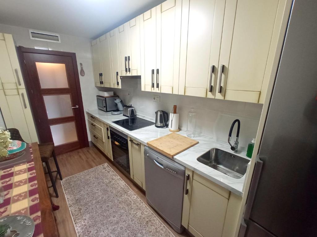 Una pequeña cocina con gabinetes blancos y un fregadero. en Casa de Nina, en Córdoba
