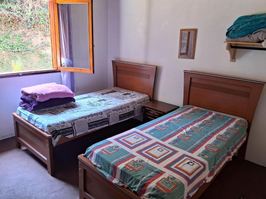 two twin beds in a room with a window at Cantinho da Serra in Santo Antônio do Pinhal