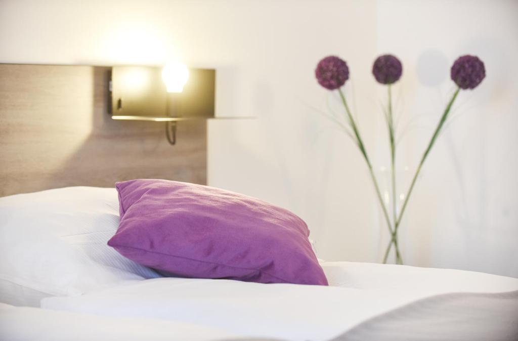 a purple pillow sitting on a bed with flowers at PRIMA Inn HOTEL & HOF NEURUPPIN - digitales & rezeptionsloses Motel in Neuruppin