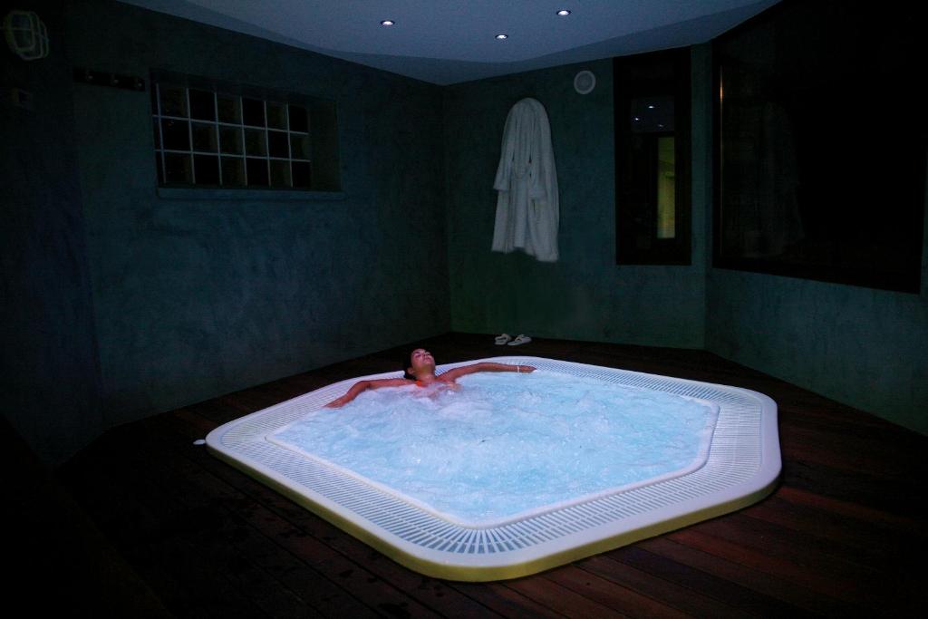 un uomo in una grande vasca da bagno in una stanza di Hotel Villa de Torla a Torla