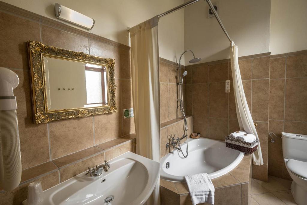 Elegant bathroom with a corner bathtub, ornate mirror, and tiled walls.