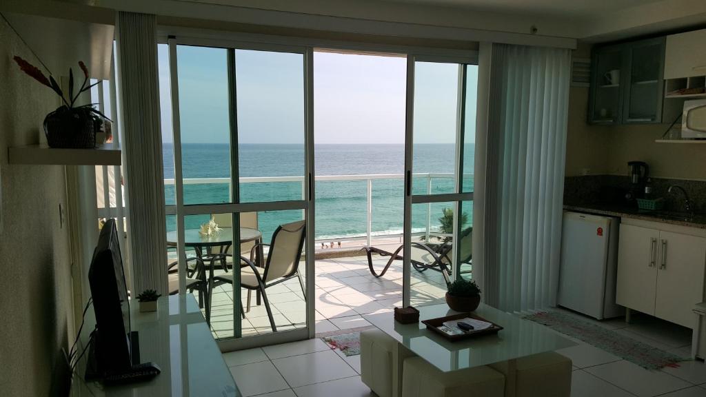 a kitchen and dining room with a view of the ocean at Cobertura em Frente ao Mar no Recreio in Rio de Janeiro