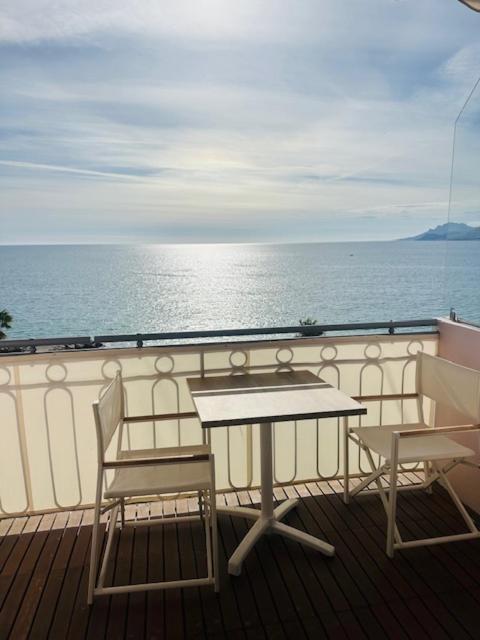 d'une table et de deux chaises sur un balcon donnant sur l'océan. dans l'établissement Appartement face mer proche palais, à Cannes