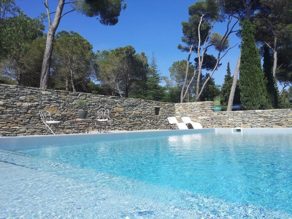 a swimming pool with chairs and a stone wall at Les Pins Domaine Russol in Laure-Minervois