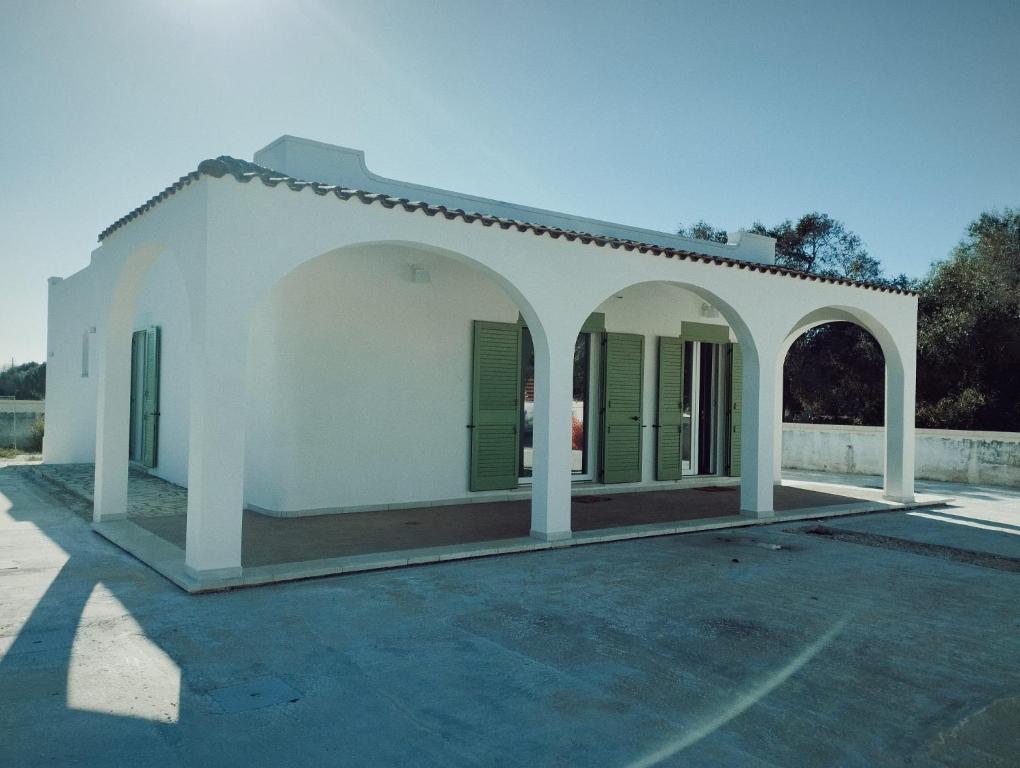 a small white building with green shutters on it at La casa tra gli Ulivi in Torre Colimena