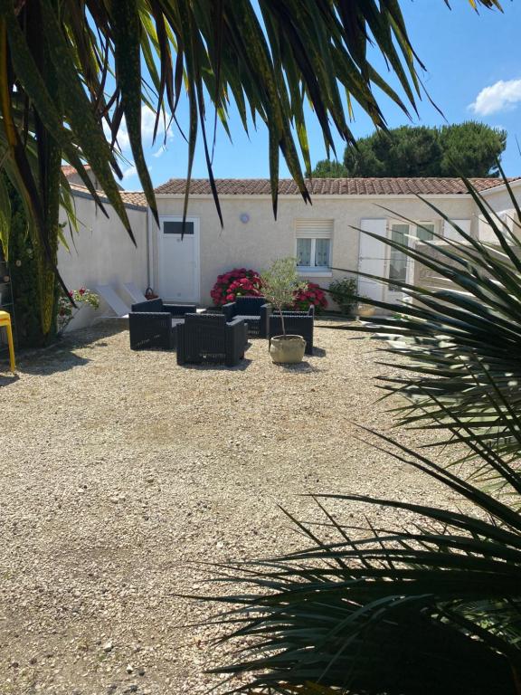 une cour avec des chaises et une maison avec un bâtiment dans l'établissement Maison indépendante en plein cœur de Dolus, à Dolus-d'Oléron