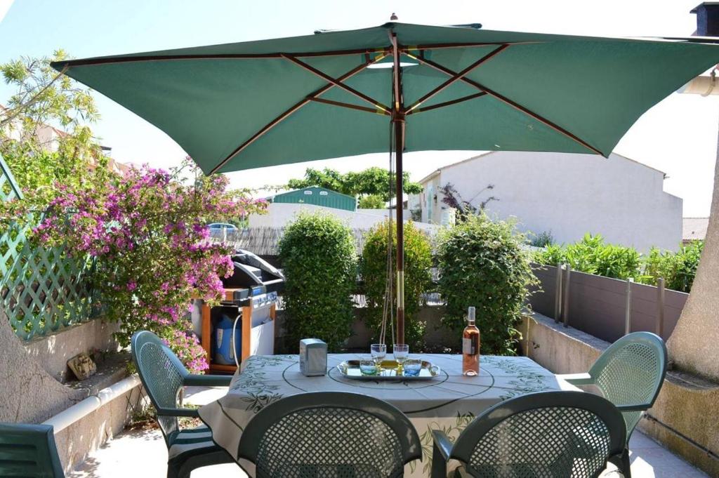 - une table avec un parasol vert sur la terrasse dans l'établissement SP060-019 Maison 3 pièces mezzanine SAINT PIERRE LA MER, à Saint Pierre La Mer
