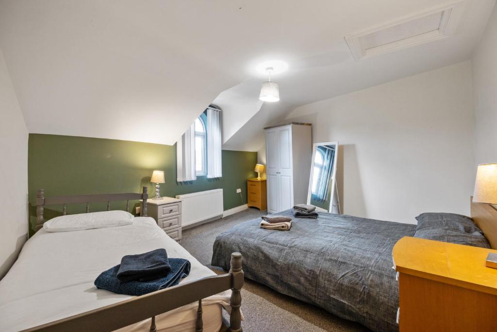 two beds in a bedroom with green walls and windows at Clondara Terrace Belfast in Belfast