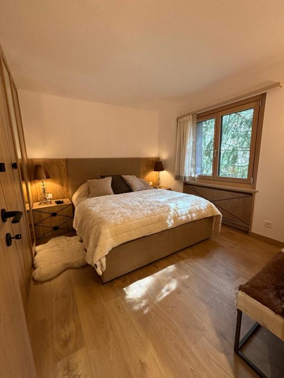 a bedroom with a large bed and a window at Appartamento nuovo Sankt Moritz Chesa arlas 3B in St. Moritz