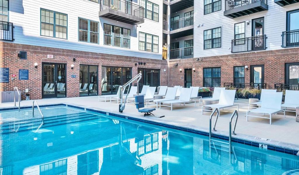 a swimming pool with white chairs and a building at 2 Story Penthouse 2 Balconies, Skyline View, Pool in Richmond