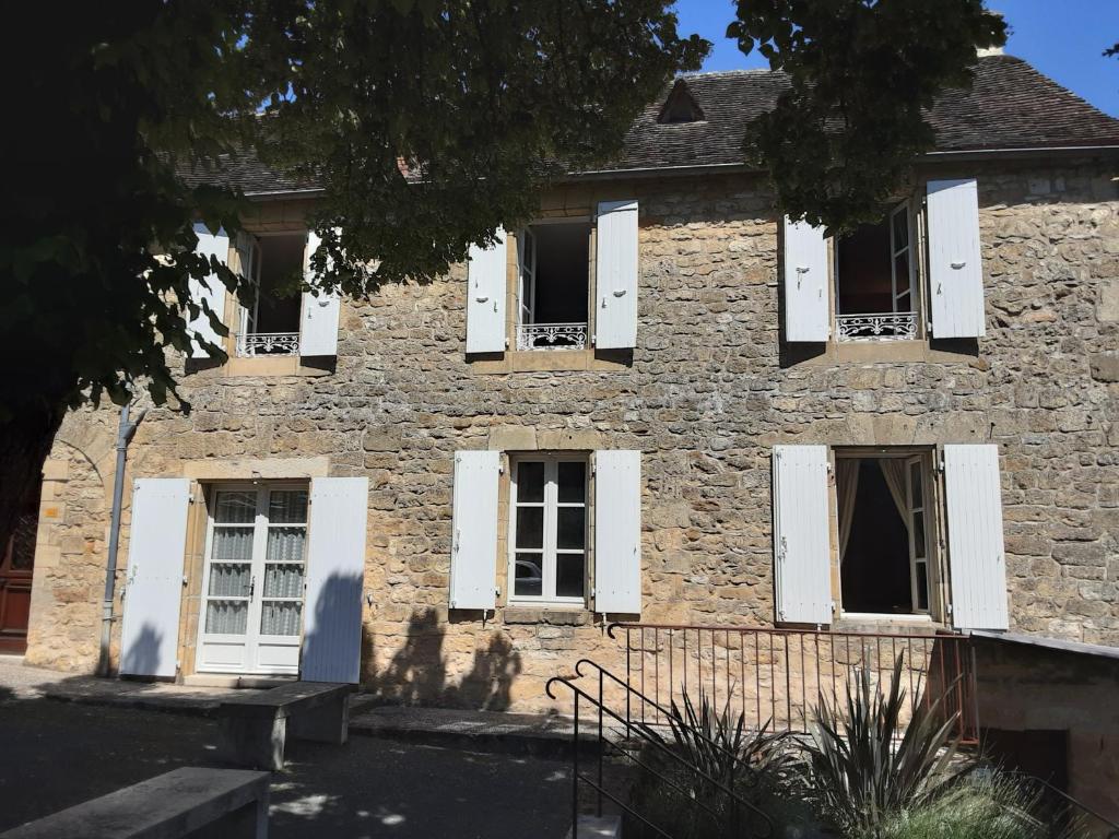 une ancienne maison en pierre avec des fenêtres blanches à volets dans l'établissement Gîte de Louis - Terrasse - Centre de Domme, à Domme