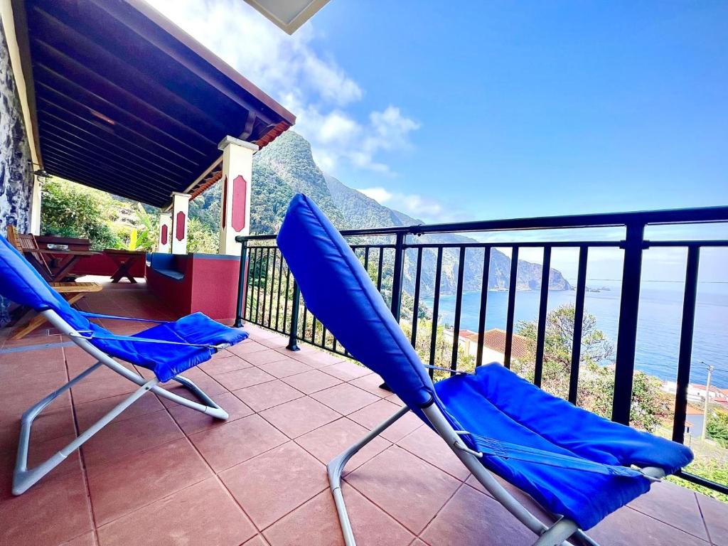 two blue chairs on a balcony overlooking the ocean at Palheiro do Farrobo in Porto Moniz