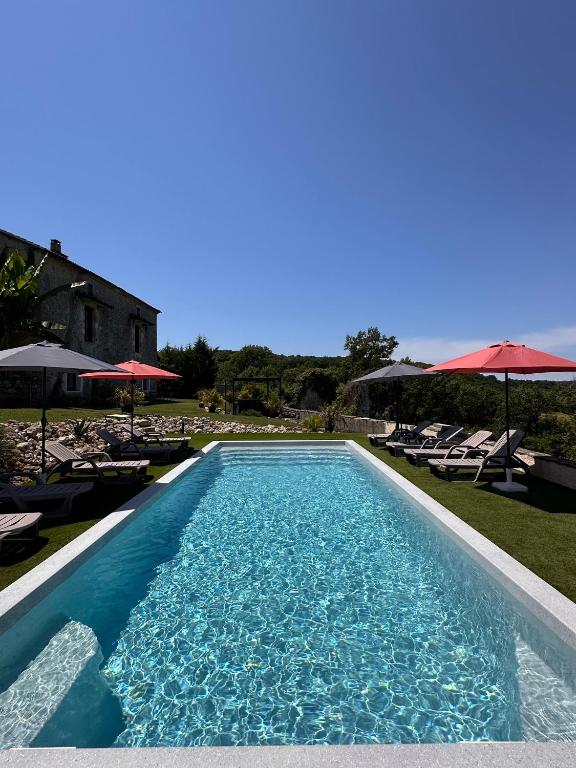 une piscine avec chaises et parasols dans une cour dans l'établissement Les Gîtes du Fournil des Moines, à Clermont-Dessous