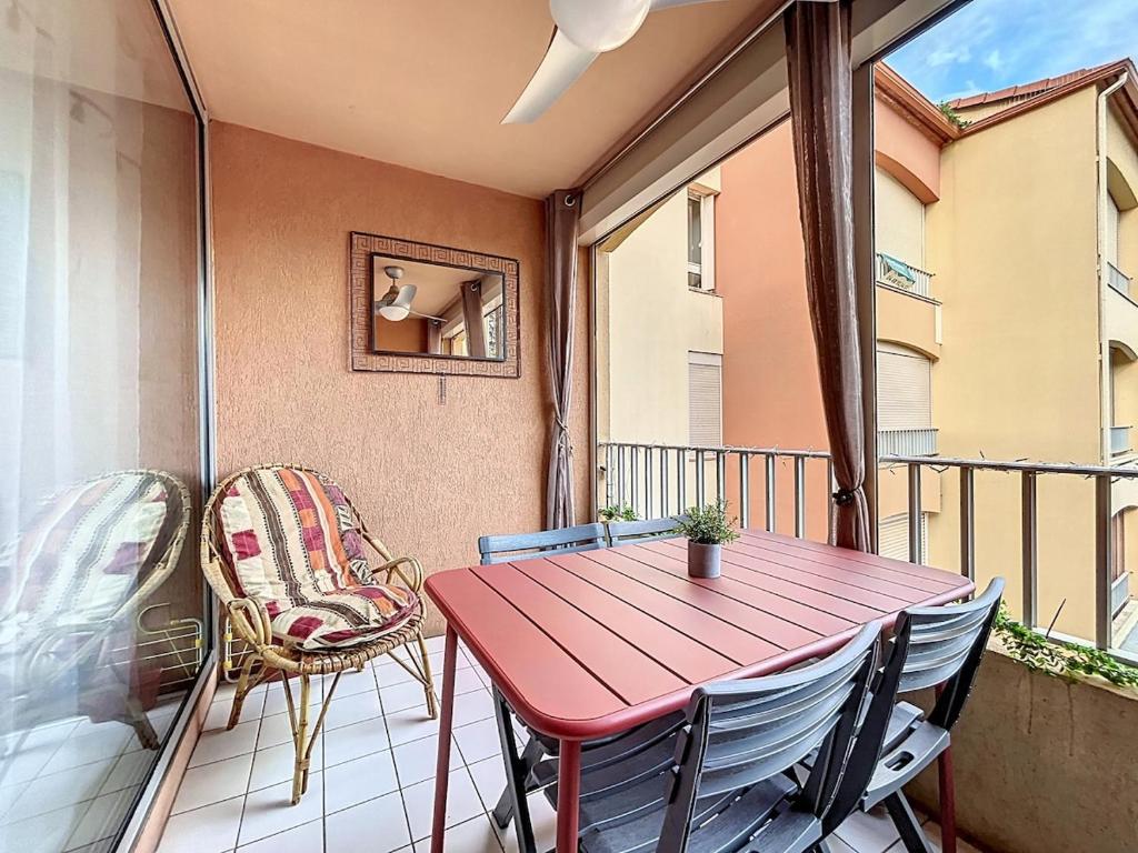 un porche avec une table rouge et des chaises sur un balcon dans l'établissement 3626-à 400m de la plage, Piscine, Parking, à Argelès-sur-Mer