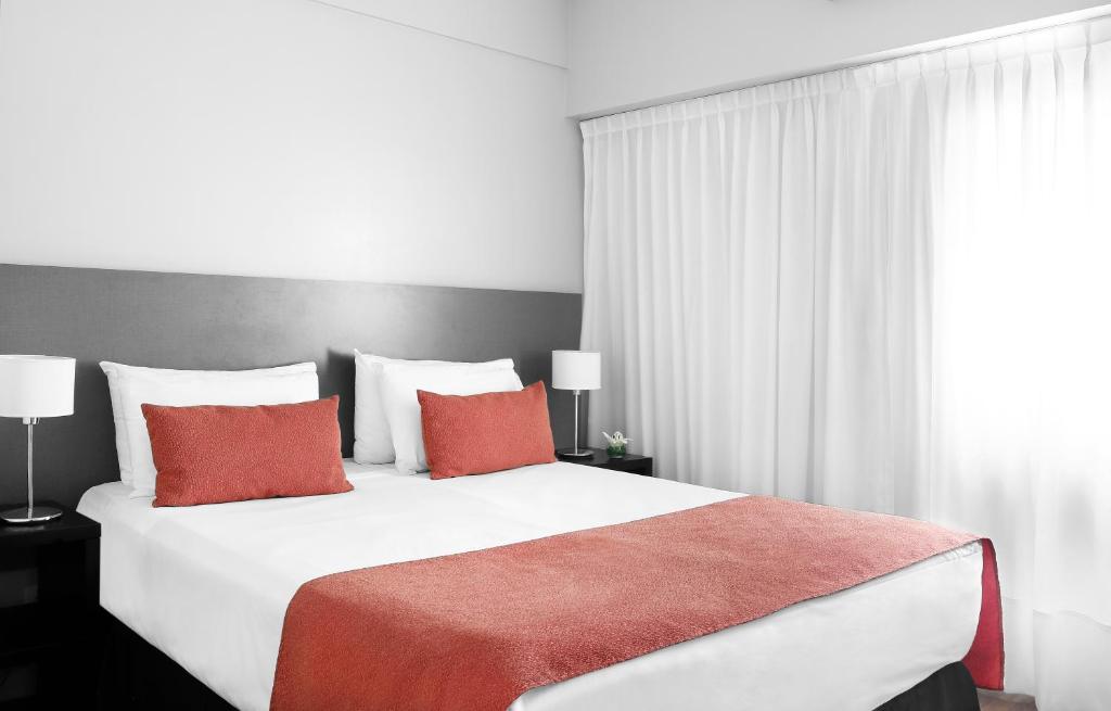 ein Schlafzimmer mit einem großen weißen Bett mit roten Kissen in der Unterkunft CH Recoleta Suites in Buenos Aires