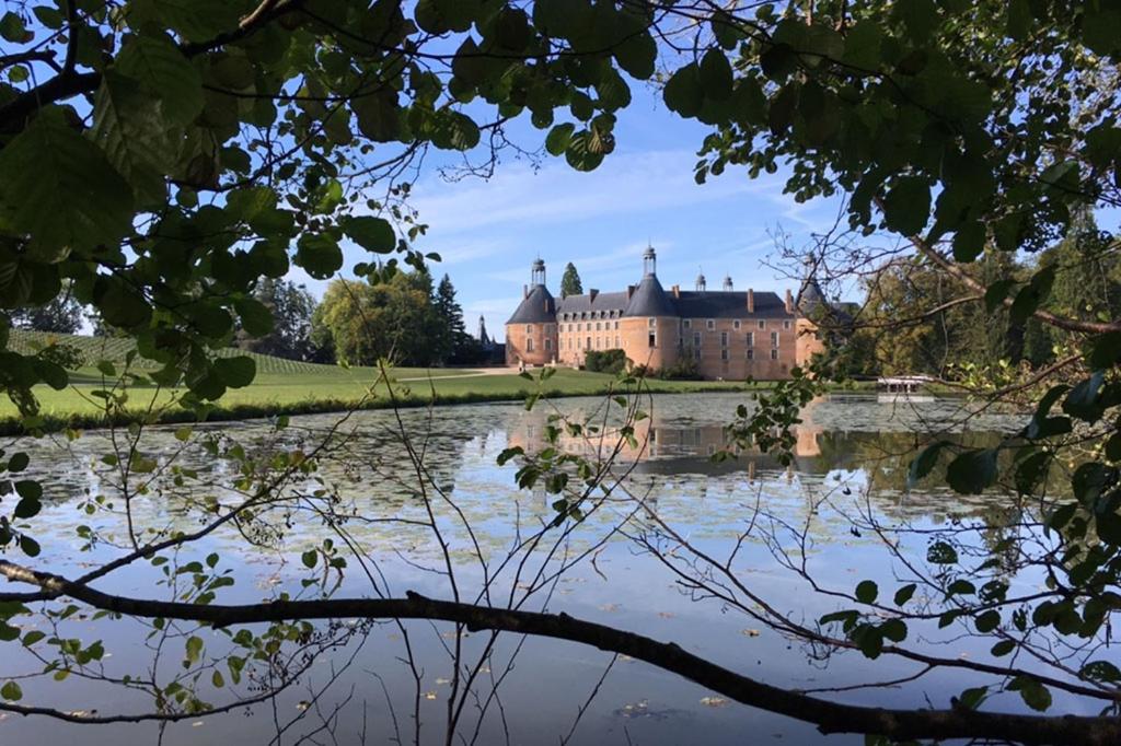 un château avec un lac en face dans l'établissement Ecuries du Château de Saint-Fargeau, à Saint-Fargeau