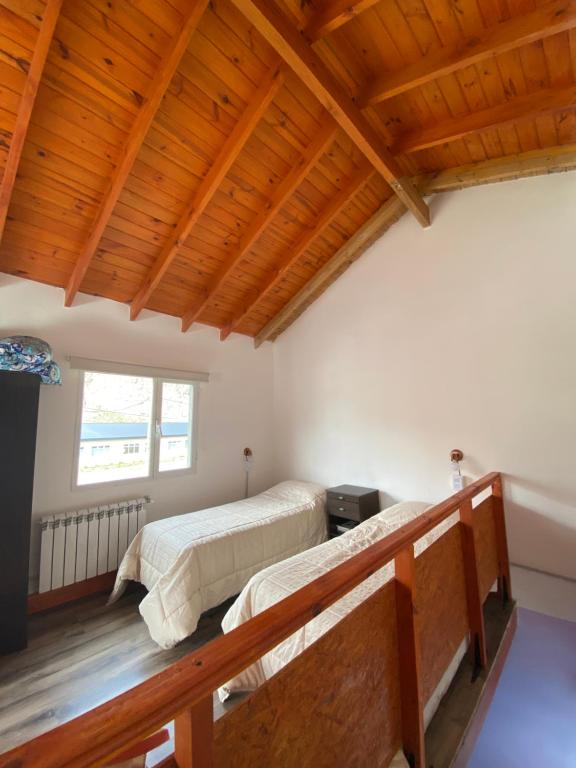 Dos camas en una habitación con techos de madera. en Cabaña Familia de Campo 3, en El Chaltén