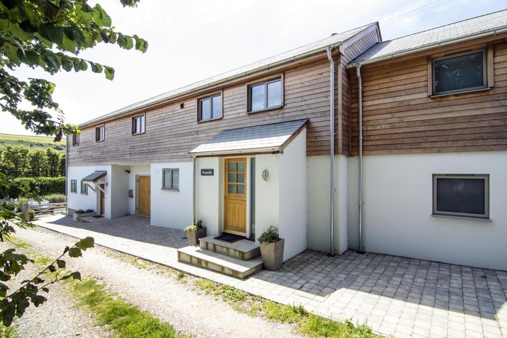 a house with a wooden facade with a driveway at Sloopside Main House in the heart of Bantham with sea views in Bantham