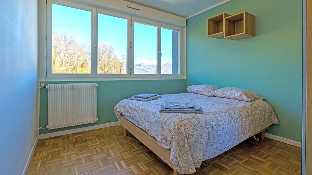 Un dormitorio con una cama con paredes y ventanas azules. en Le Belvédère - WIFI Fibre - Parking gratuit, en Gap