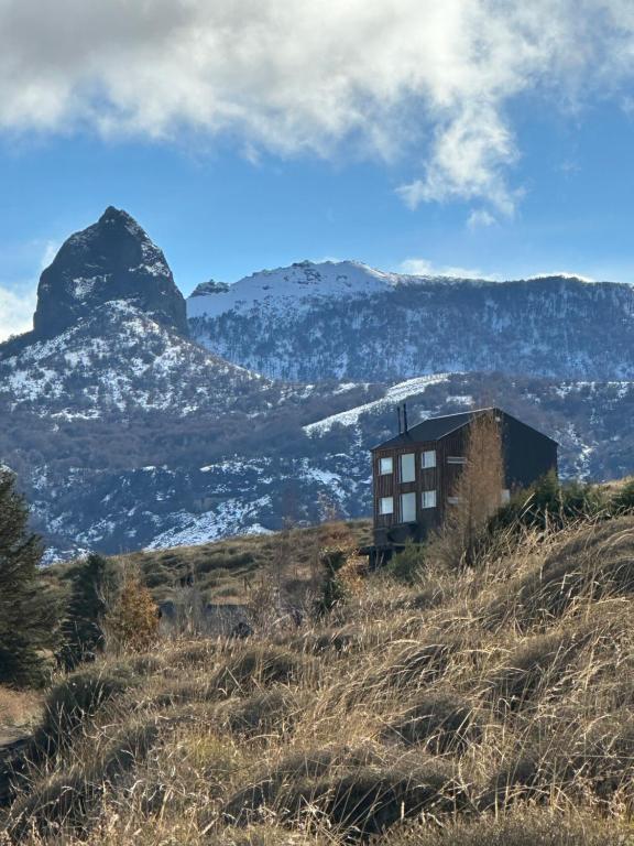 a building on a hill with mountains in the background at Cabañas Lodge Puerta Roja in Los Helechos
